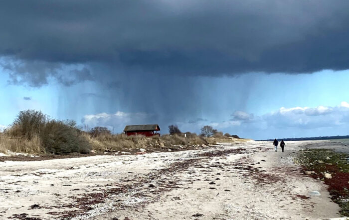 Fußgänger am Strand mit dunklen Wolken