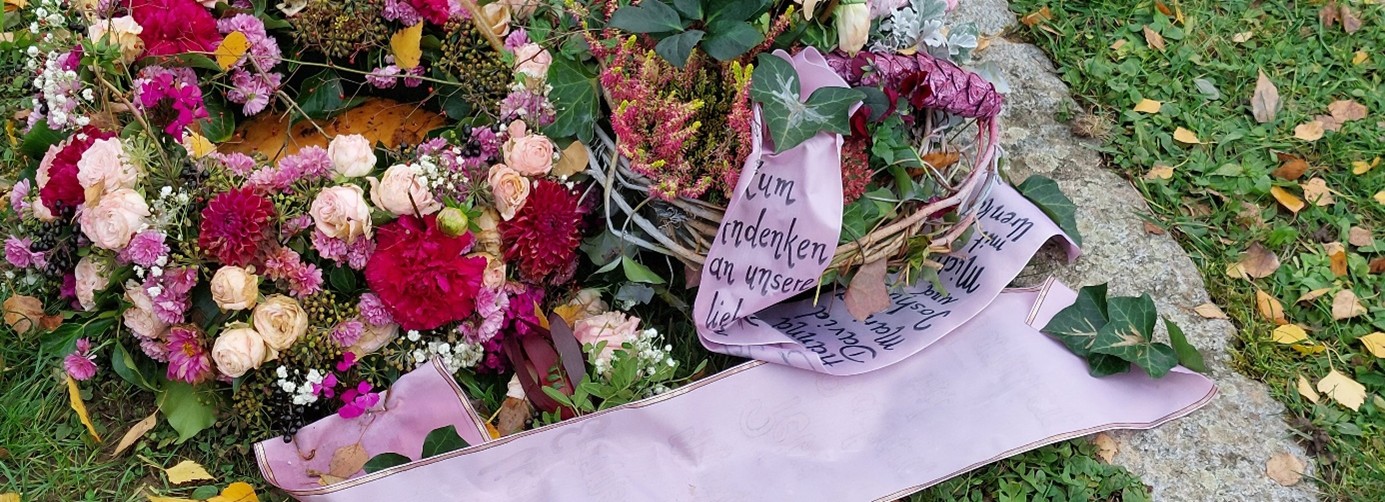 Grab mit Blumengesteck und Grußband- Trauerschleife