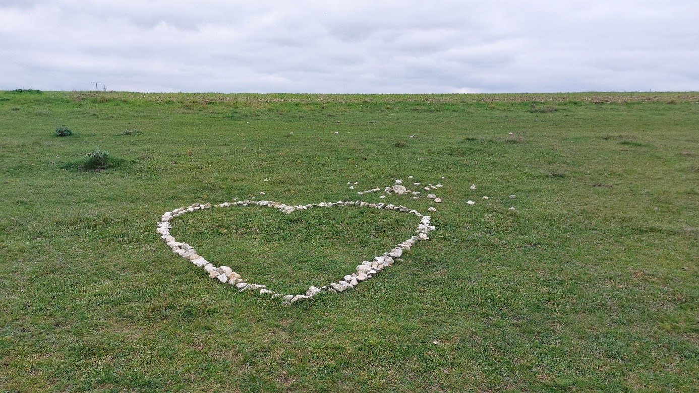 Herz aus Steinen auf grünem Feld